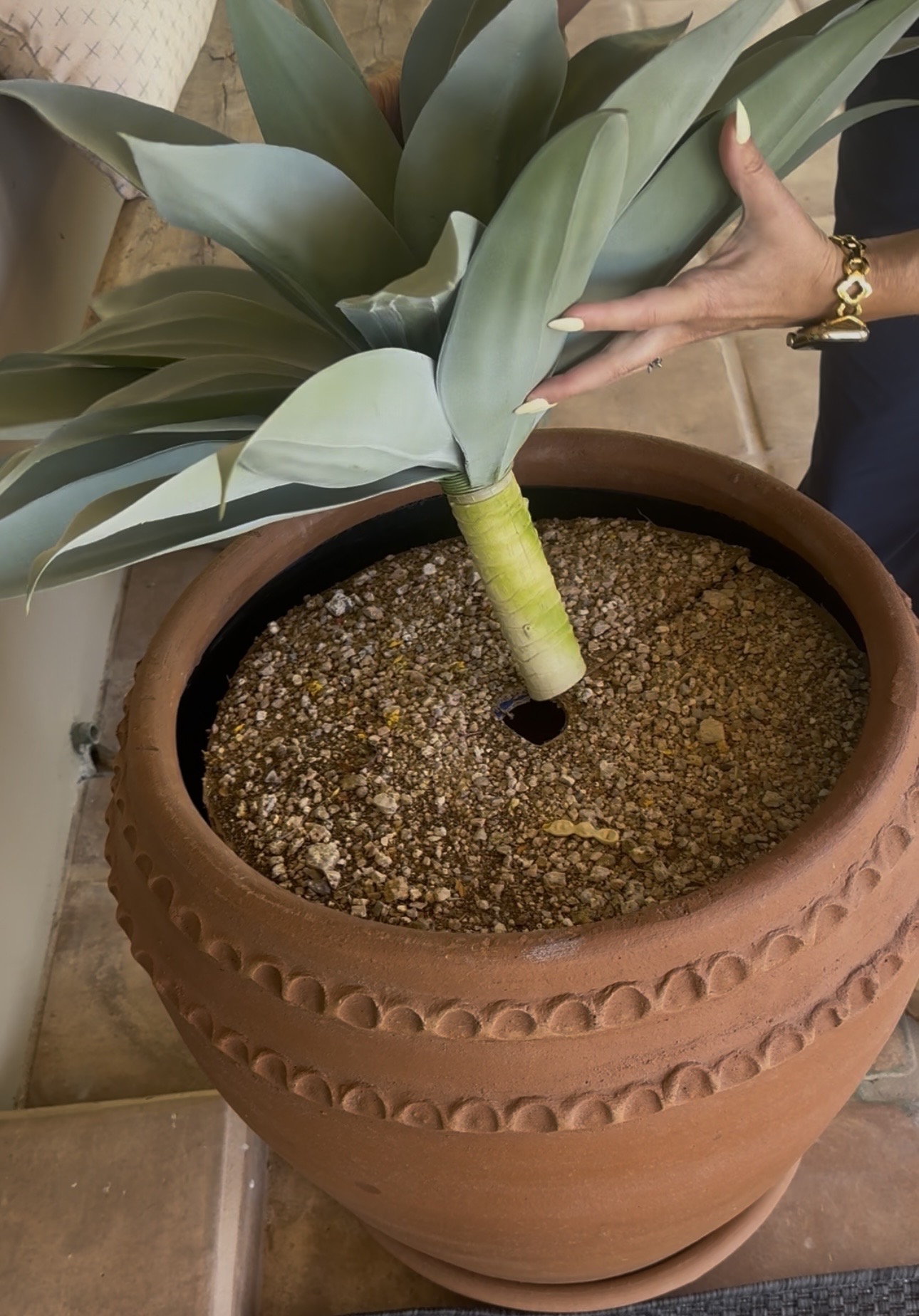 Faux agave plant stem being inserted through the center hole into the pot