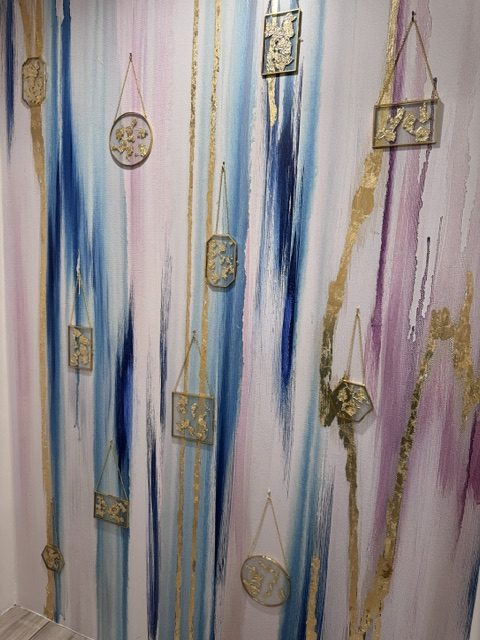 Gold leaf filled hanging frames on a watercolor wallpaper mural